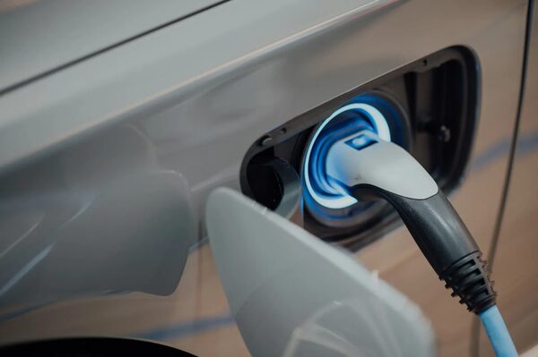 A charging cable plugged into the illuminated charge port of an electric car