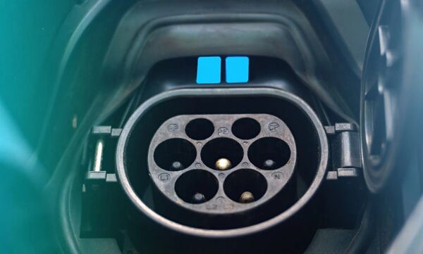 A close-up of a Type 2 EV charging socket on a car with its charging port flap open