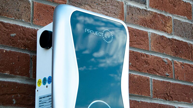 A Project EV wall-mounted electric car charge point installed on a red brick wall