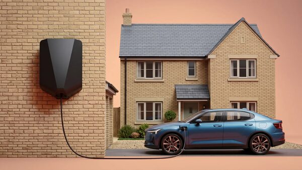 A blue electric car charging from a black wall-mounted EV charger outside a brick detached house