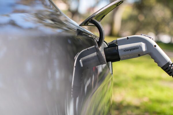 A Chargepoint EV charging cable plugged into the charging port of a dark car outdoors