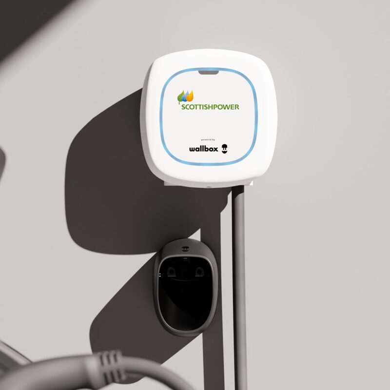 A white ScottishPower-branded Wallbox EV charger mounted on a wall with its cable holder and charging cable