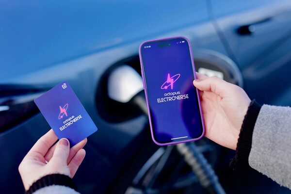 Hands holding an Octopus Electroverse app on a phone and an Electroverse charge card in front of a plugged-in electric car