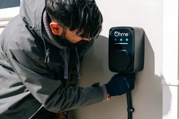 An installer plugging a cable into a wall-mounted Ohme home EV charge point