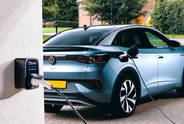 An Ohme ePod wall-mounted EV charger on a house wall charging a blue Volkswagen ID.5 on a driveway