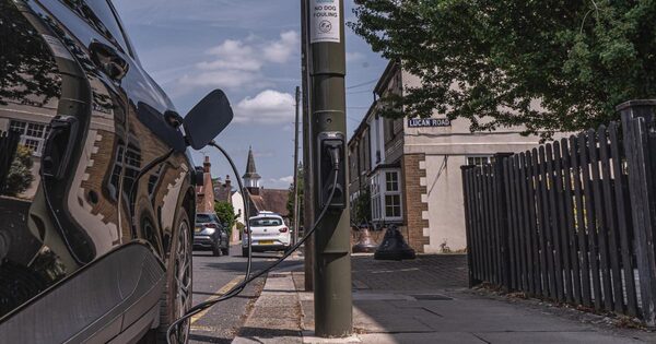 An electric car charging from a lamp-post-mounted EV charge point on a UK residential street