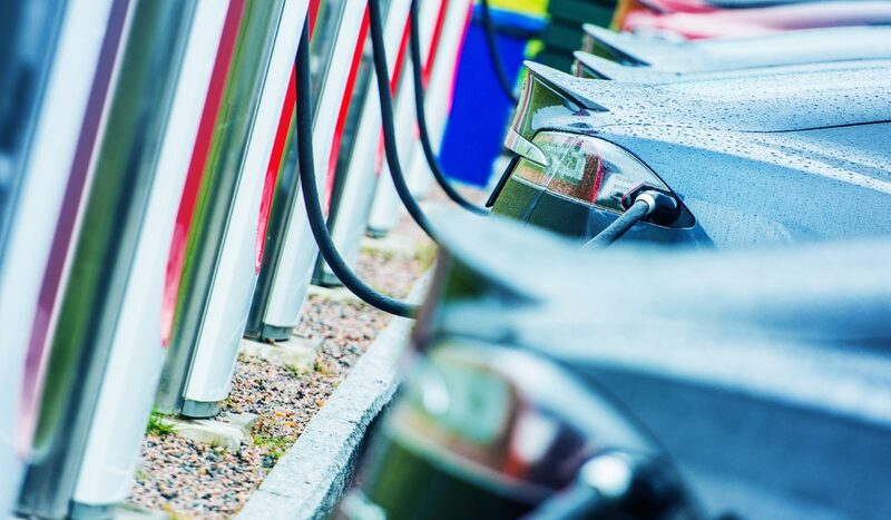 Electric cars plugged into a row of public EV charging points