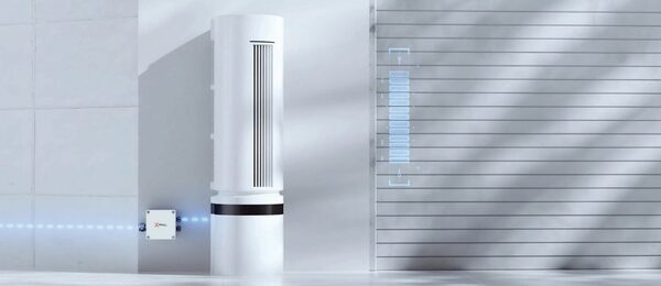 A tall white SolaX home battery storage unit standing against a grey wall with a small wall-mounted inverter box
