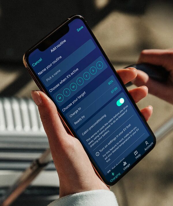 A hand holding a smartphone displaying the Ohme app's Add routine screen for scheduling EV charging