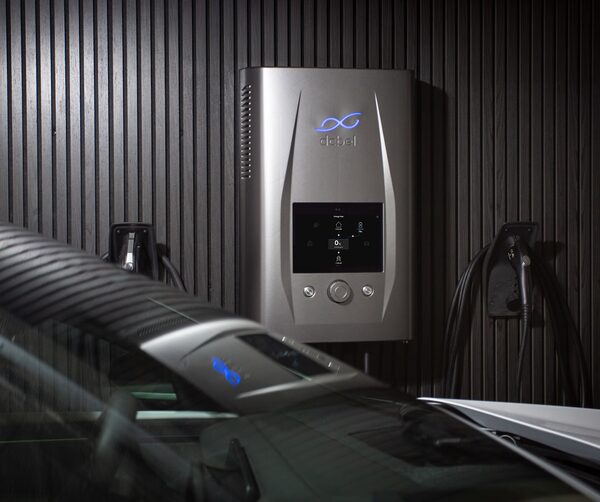 A dcbel wall-mounted bidirectional EV charger with two charging cables next to a parked car