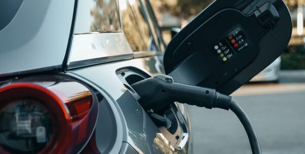 A charging cable plugged into the charging port of a grey electric car