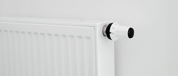 A thermostatic radiator valve dial fitted to the end of a white panel radiator