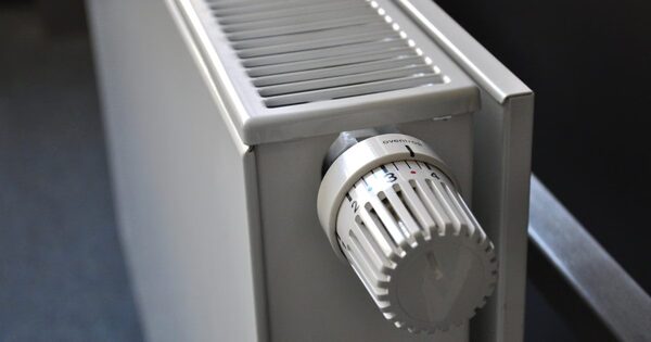 A close-up of a white panel radiator with a thermostatic radiator valve dial