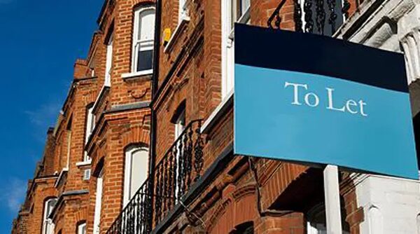 A 'To Let' sign outside a red-brick terraced house