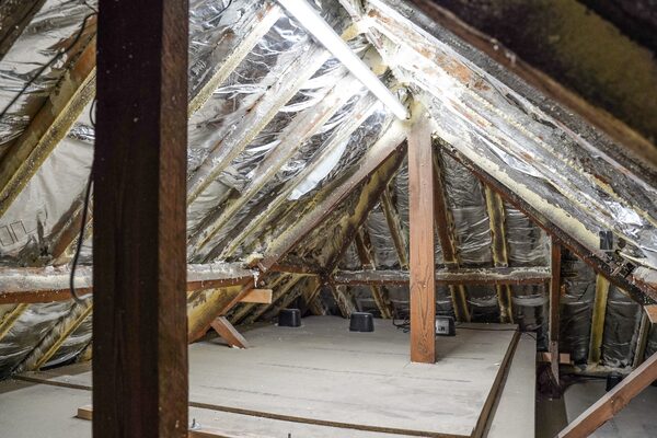 A loft interior with reflective foil insulation fitted between the rafters over spray foam, with boarded floor and roof timbers