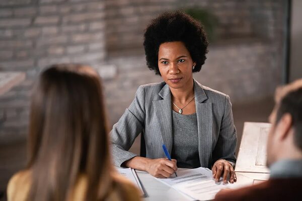 An adviser in a grey blazer going over paperwork with a couple at a table