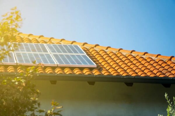 Solar panels mounted on a terracotta-tiled roof in sunlight