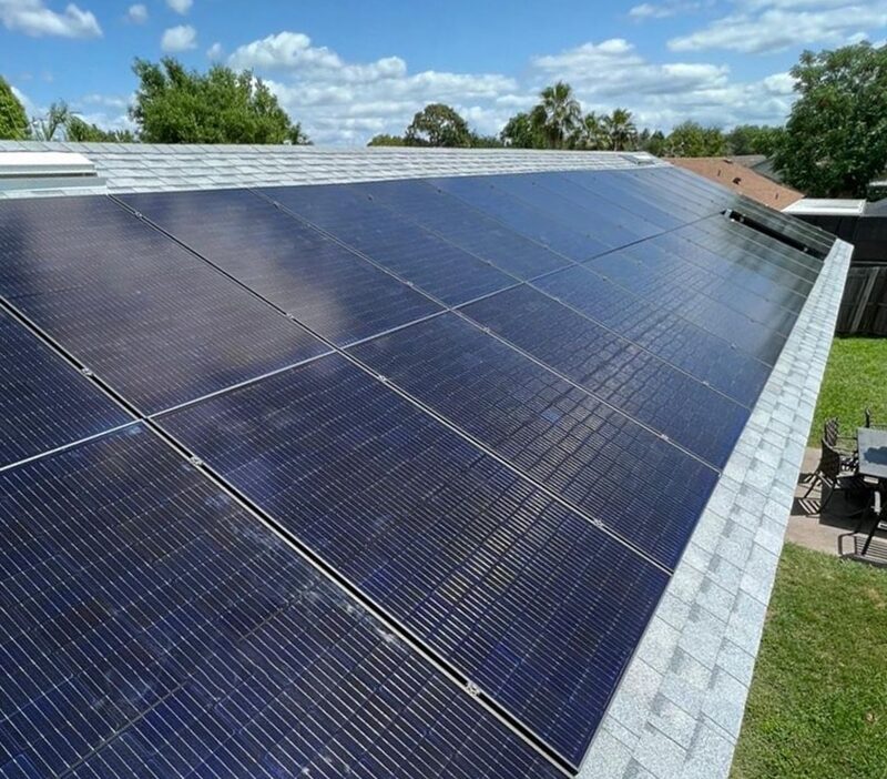 A large array of solar panels covering the shingled roof of a suburban house