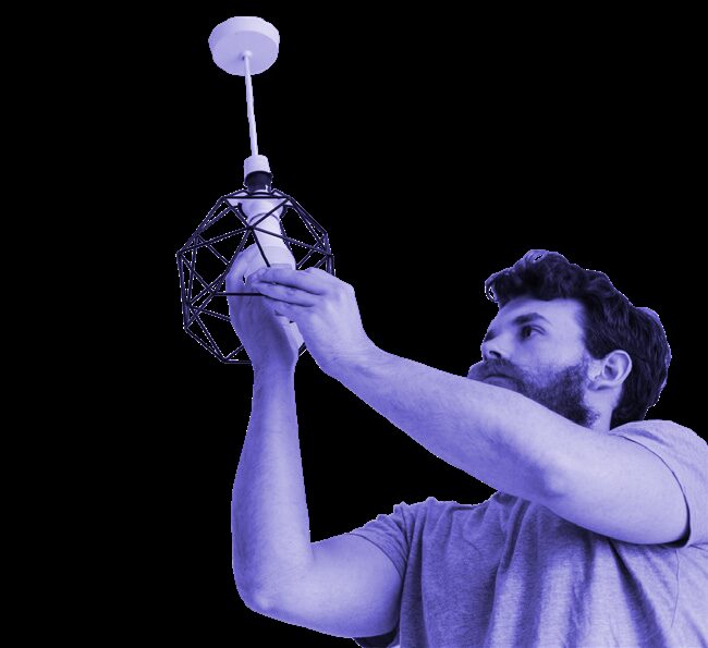 A man fitting a light bulb into a geometric wireframe pendant lamp against a white background