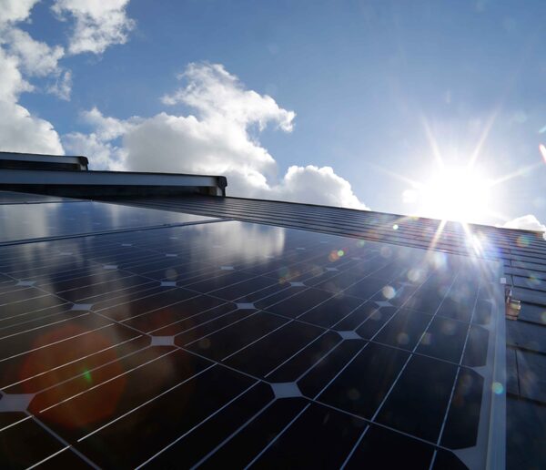 Solar panels installed on a roof with bright sunshine and clouds in the background