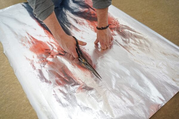 A person cutting a roll of reflective foil insulation material with scissors