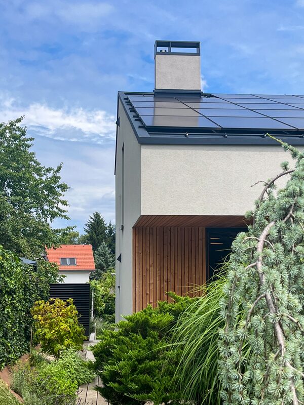 A renovated house with rooftop solar panels seen from the garden