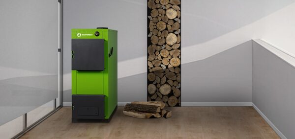A green Ecoforest wood-pellet biomass boiler standing in a minimalist room next to a stack of firewood
