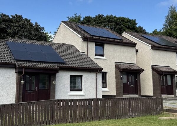 A row of UK social houses with solar panels installed on their tiled roofs