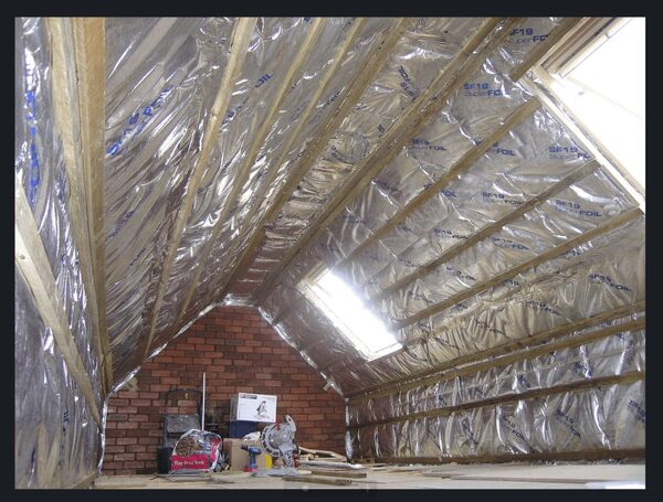 A loft with SuperFoil SF19 foil insulation fitted between the rafters, with a skylight and tools on the floor
