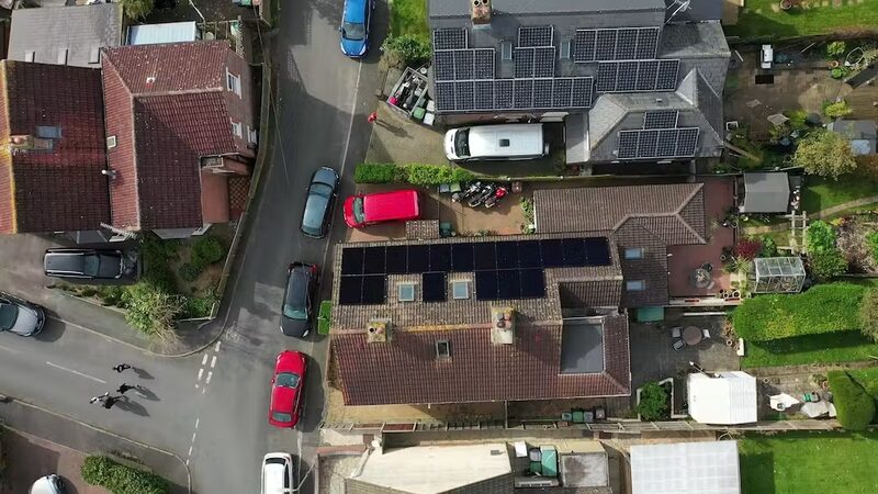 Aerial view of UK homes with rooftop solar panel arrays on tiled roofs
