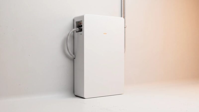 A white wall-mounted home battery storage unit with flexible conduit connections against a plain wall