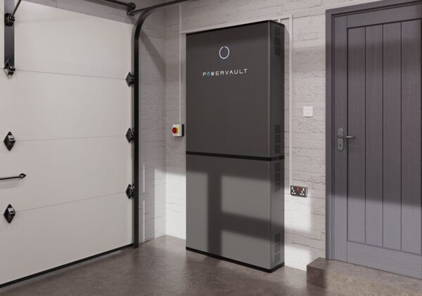 A Powervault home battery unit installed on the wall of a garage next to a grey door