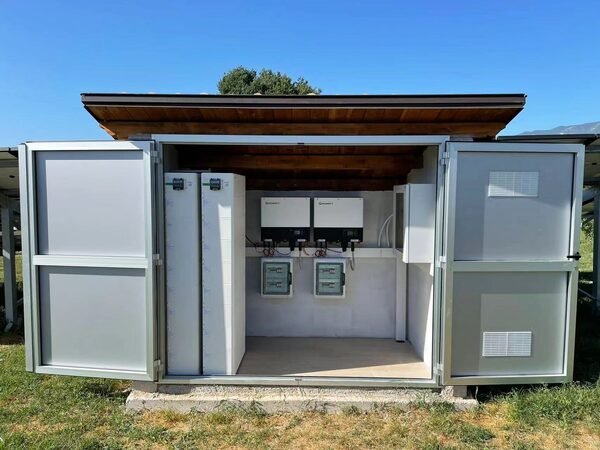 An outdoor equipment enclosure containing Growatt inverters, battery storage units and electrical distribution boxes, part of a residential solar installation
