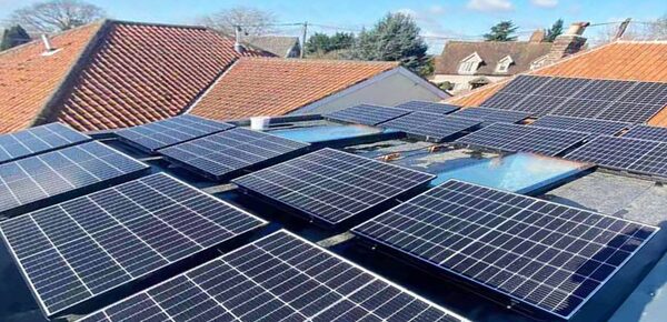 A large array of solar panels installed on a flat roof among UK houses with tiled roofs