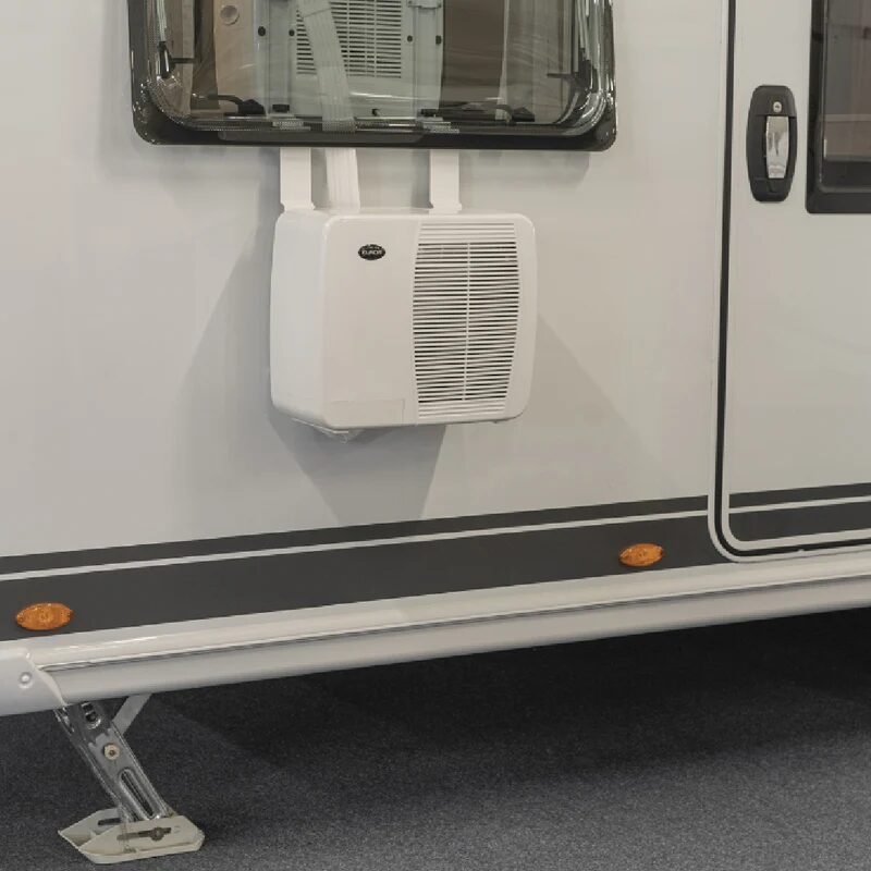 A white split caravan air conditioner outdoor unit mounted on the exterior wall of a caravan below a window