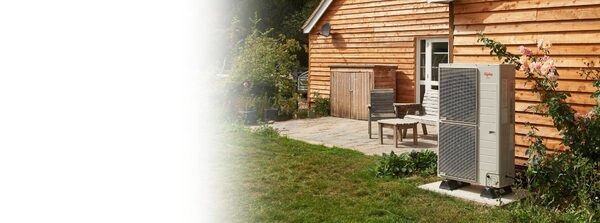 An Alpha air source heat pump unit installed outside a wooden-clad house beside a patio