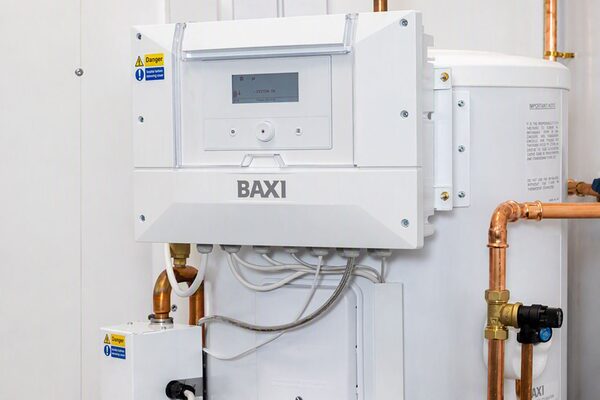 A Baxi pre-plumbed heat pump cylinder with control unit installed in a home airing cupboard with copper pipework