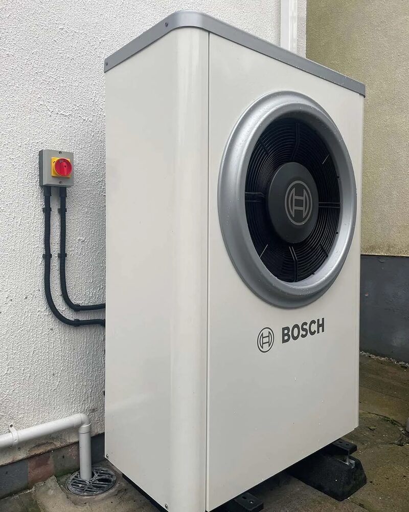A Bosch air source heat pump unit installed outside a house wall
