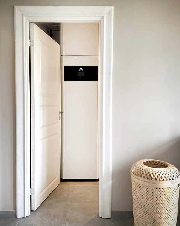 A white CTC heat pump indoor unit installed in a cupboard, seen through an open doorway