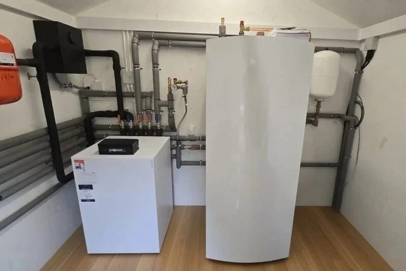 A ground source heat pump unit, cylinder and pipework installed in a plant room