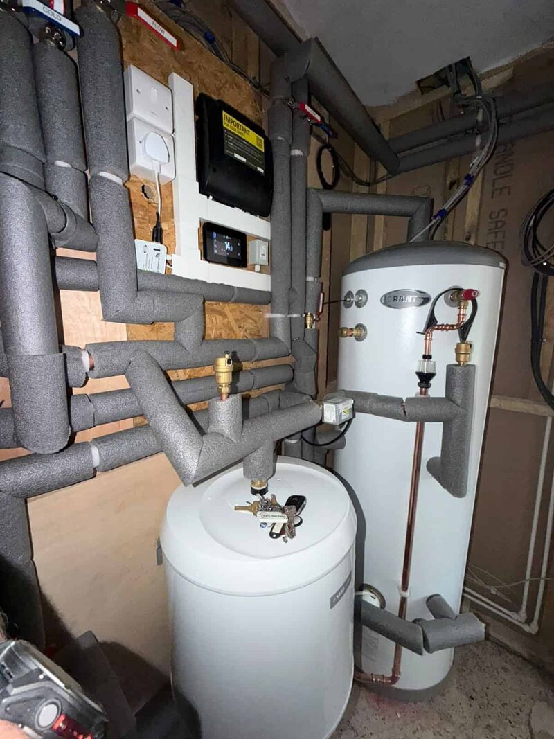 A heat pump plant room with insulated pipework, Grant cylinder, buffer vessel and heating controls