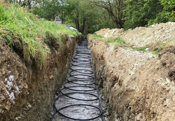 A slinky ground-loop pipe laid in a dug trench for a ground source heat pump installation