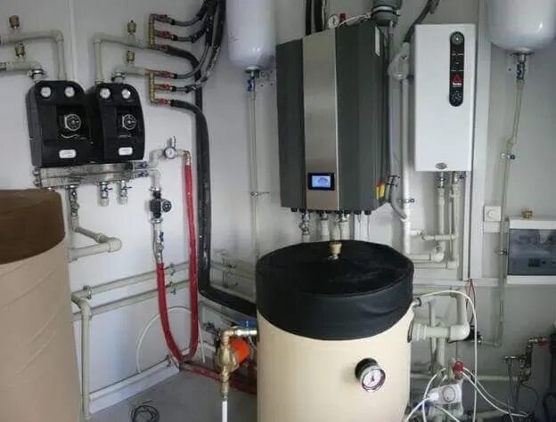 A heat pump and heating system installation with a buffer tank, pumps and pipework in a plant room