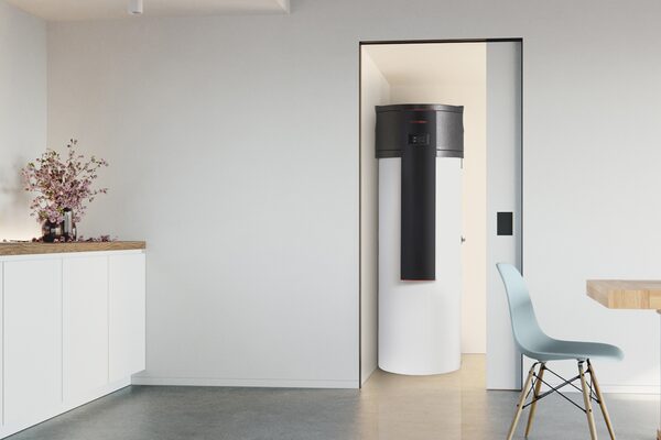 A Kronoterm heat pump water heater cylinder installed in a cupboard off a modern living room