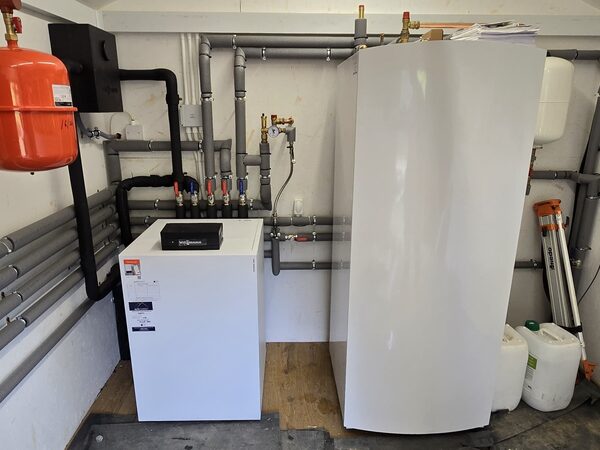 A Viessmann heat pump cylinder and buffer tank installed with grey pipework, expansion vessel and valves in a plant room