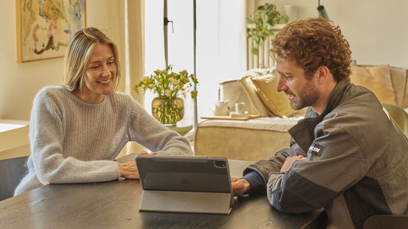 A Daikin engineer and a woman at a kitchen table looking at a tablet together