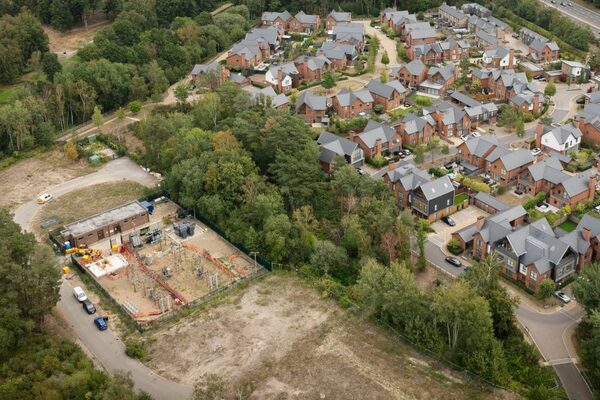 An aerial view of an electricity substation with transformers under construction beside a brick housing estate