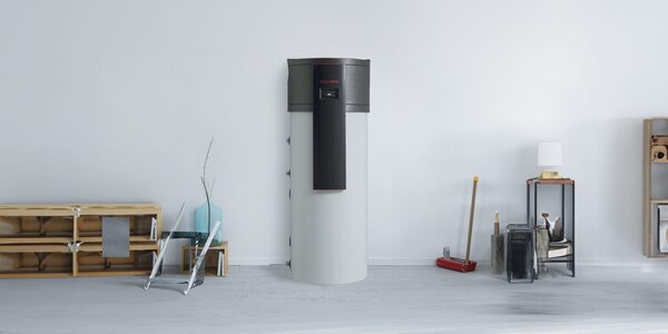 A Kronoterm domestic hot water heat pump cylinder standing against a white wall in a styled room