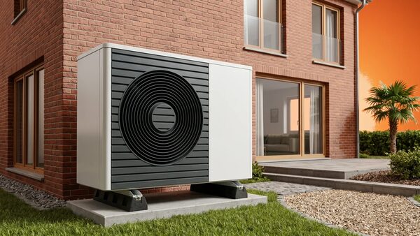 An air source heat pump unit installed on a concrete pad outside a modern brick house