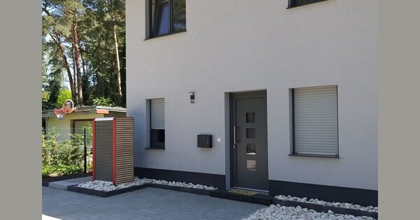 A heat pump outdoor unit installed beside the entrance of a modern semi-detached house